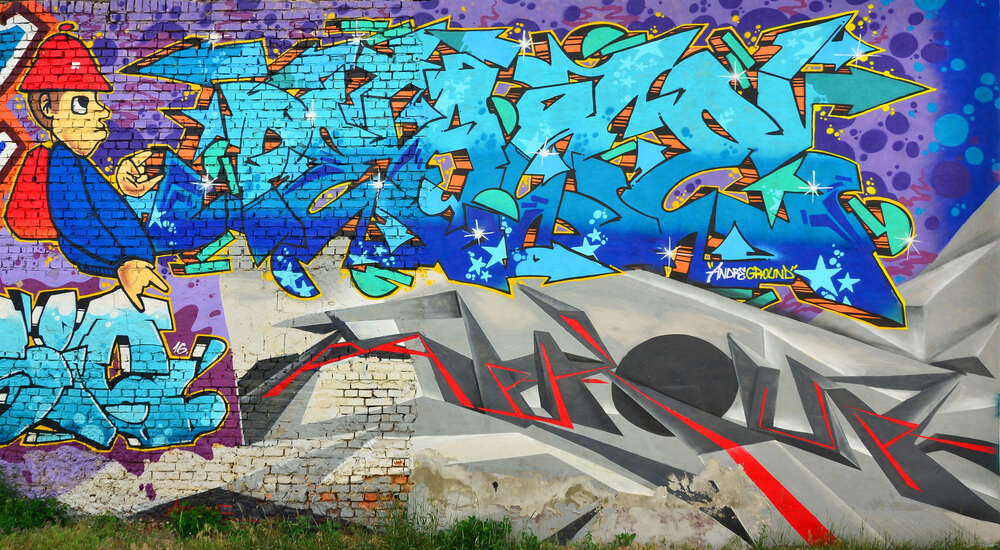 Vibrant street art mural featuring colorful graffiti and a cartoon character on a brick wall.