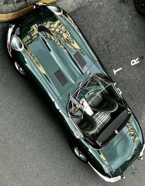 Aerial view of a classic green sports car parked on a street, showcasing its sleek design and vintage appeal.