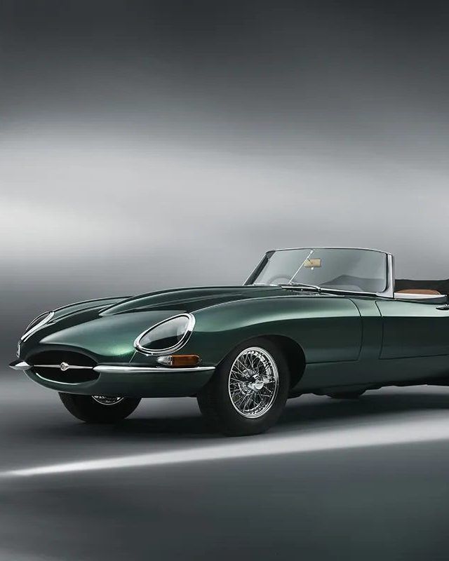 Vintage green convertible sports car with sleek design on a gray background. Classic automotive elegance.