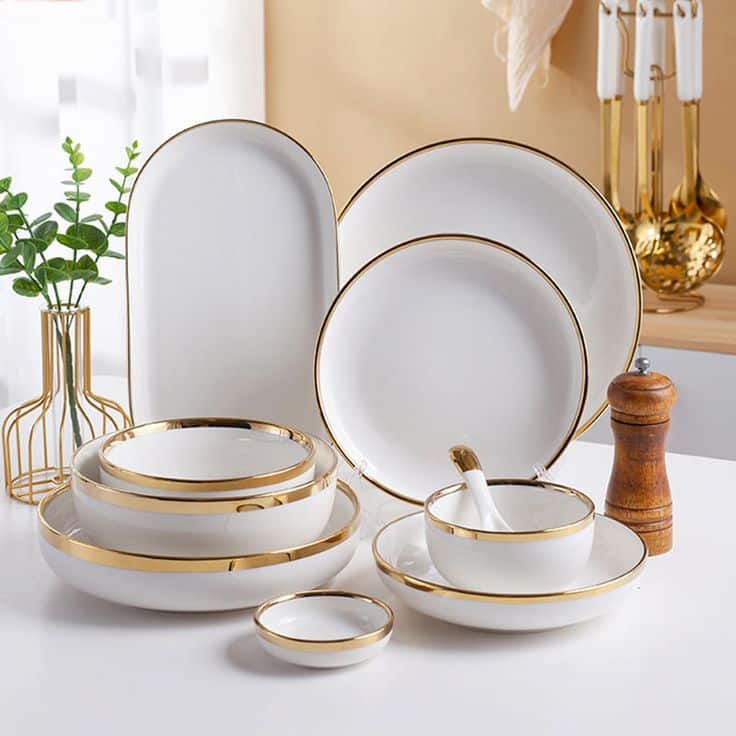 Elegant white dinnerware set with gold rims on a table, enhancing dining aesthetics for special occasions.