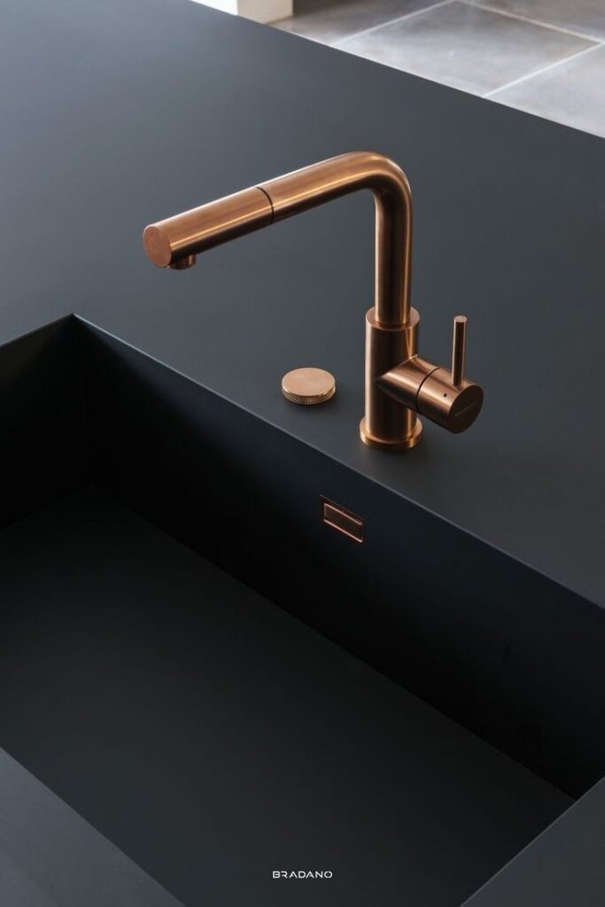 Elegant bronze faucet and modern black sink on sleek kitchen countertop.