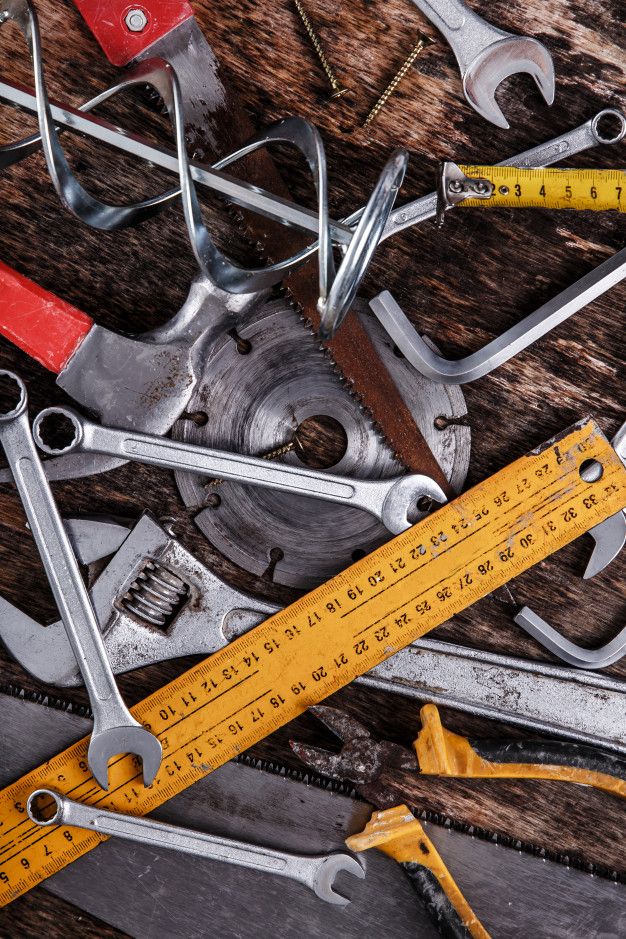 Assorted hand tools on a wooden surface, including wrenches, saw, ruler, and pliers, ideal for DIY enthusiasts.