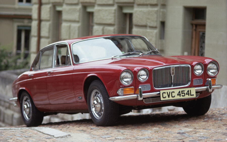 Classic red sedan parked on cobblestone street, showcasing vintage British automotive design.