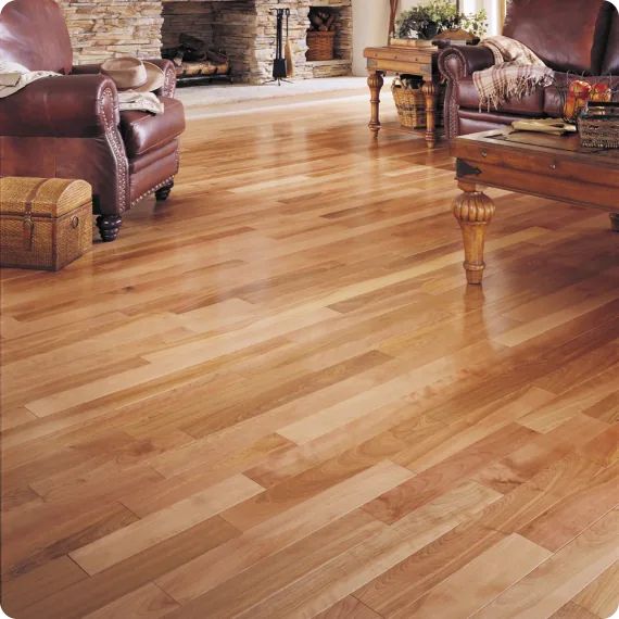 Cozy living room with polished hardwood floors, leather sofas, and a stone fireplace, creating a warm, inviting atmosphere.