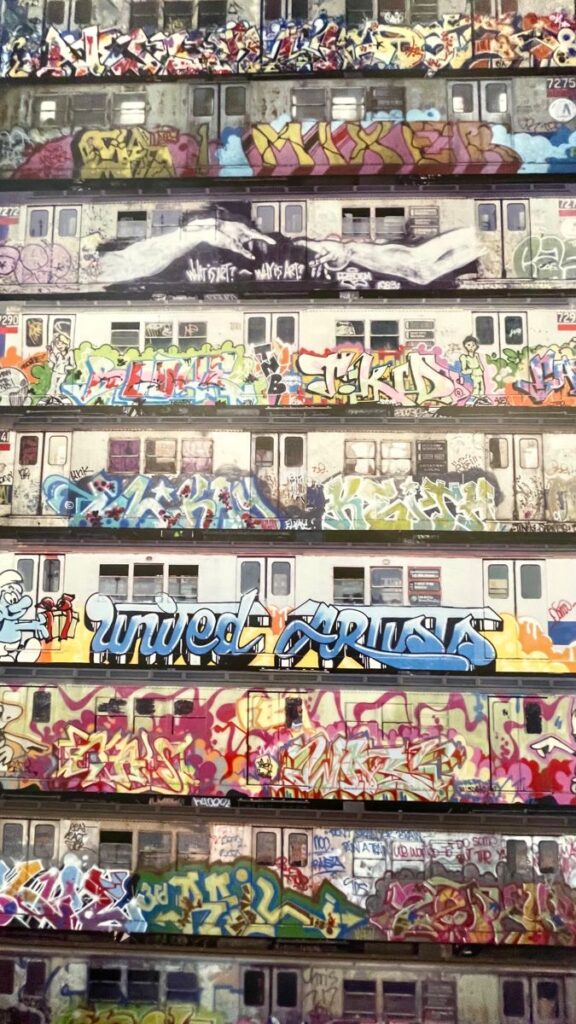 Colorful graffiti art covers multiple subway train cars in a vibrant urban scene.