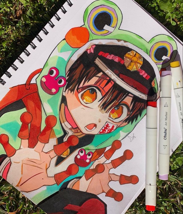 Colorful anime character drawing with frog-themed jacket and vivid markers on grass background.