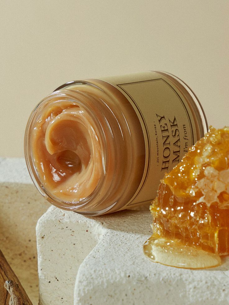 Honey face mask jar with honeycomb on stone surface, showcasing natural skincare ingredients.