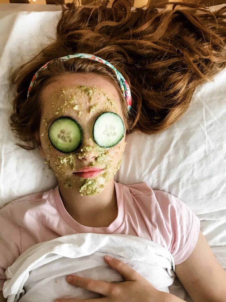 Young girl relaxing with a cucumber face mask and eye slices, promoting natural skincare and beauty treatment.