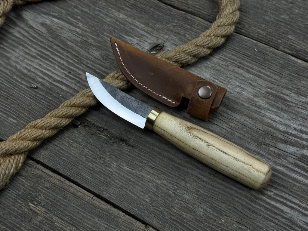 Wooden-handled knife with leather sheath on rustic wooden background, ideal for camping and outdoor activities.