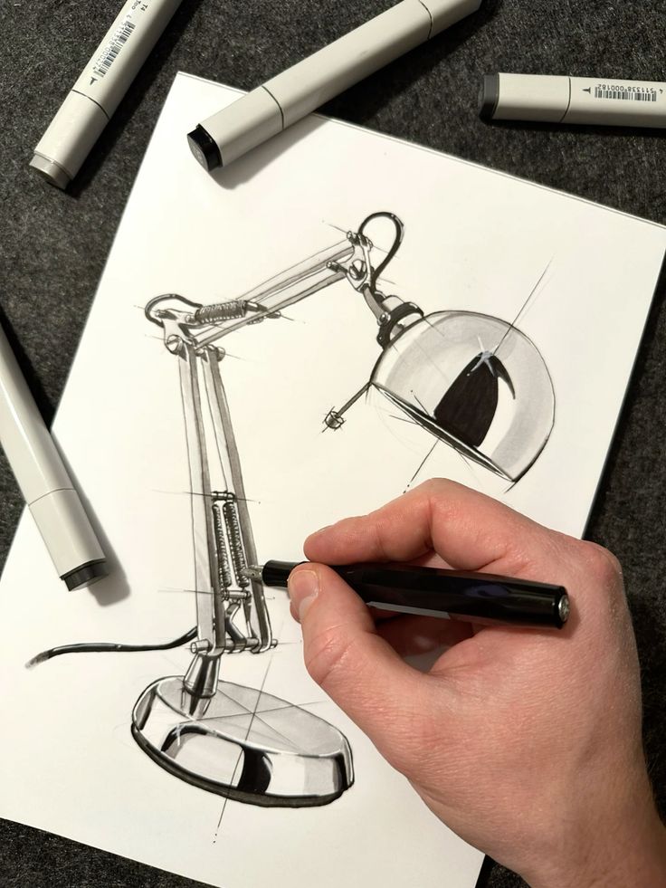 Hand drawing desk lamp design with black markers on white paper.