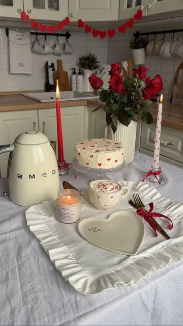 Romantic kitchen setup with cake, roses, heart-shaped plate, and candles for Valentine's celebration.