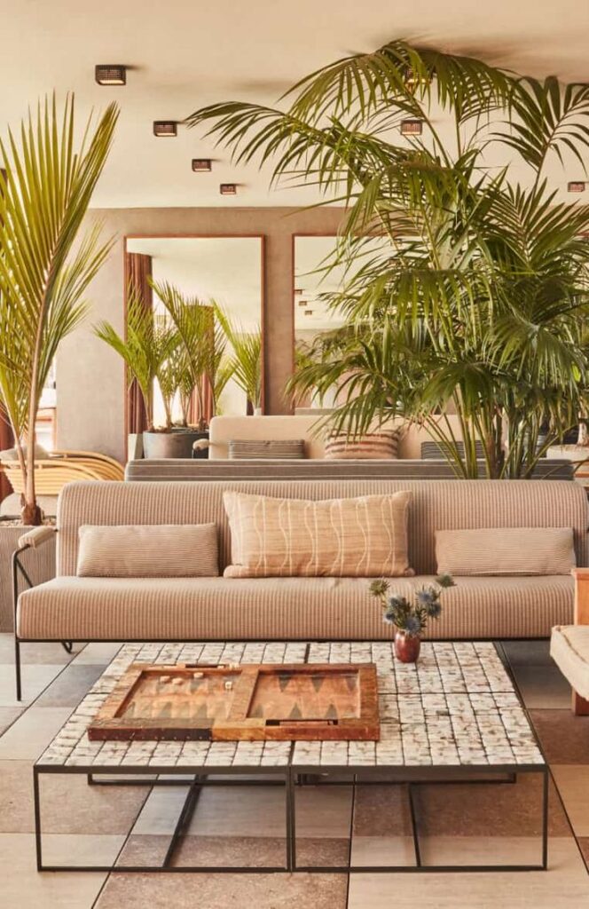 Modern living room with striped sofa, large plants, and tiled coffee table, creating a serene and stylish ambiance.