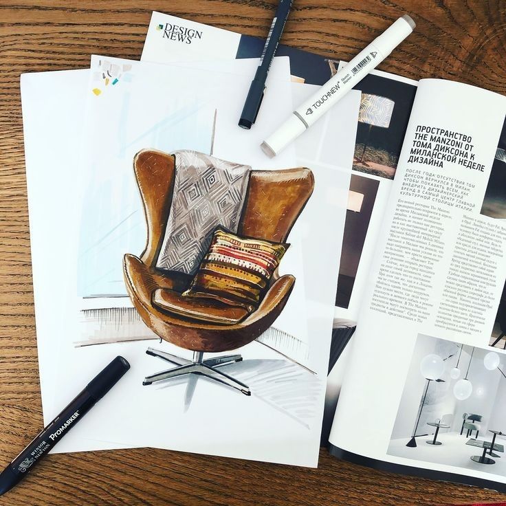 Chair sketch with vibrant pillows on a wooden table surrounded by design magazines and markers.