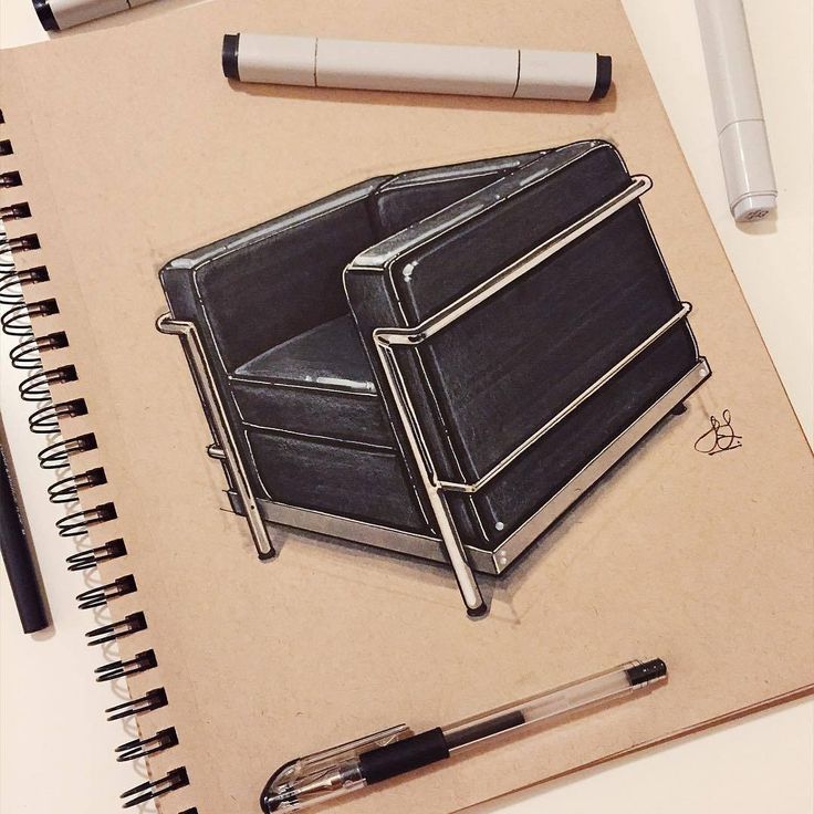 Design sketch of a modern armchair on a notebook page, surrounded by pens and markers for artistic rendering.