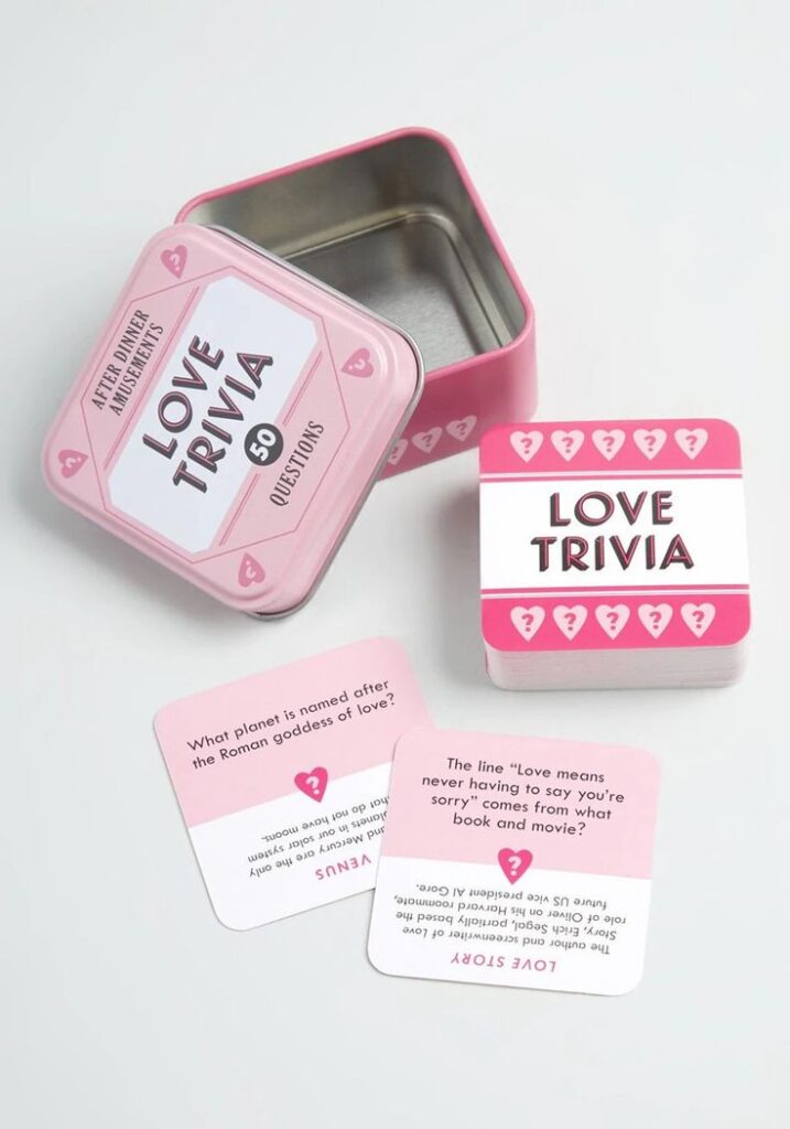 Love Trivia card game with pink tin box and question cards, perfect for romantic quizzes and fun after-dinner activities.