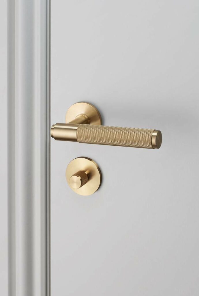 Elegant brass door handle and lock on a smooth gray door.