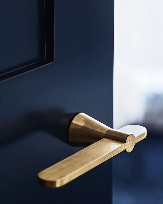 Close-up of a modern brass door handle on a sleek black door, showcasing contemporary interior design elegance.