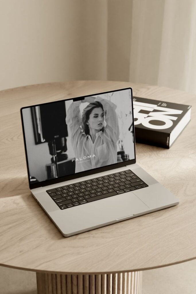 Laptop on table displaying black and white fashion image with the word Paloma on screen.