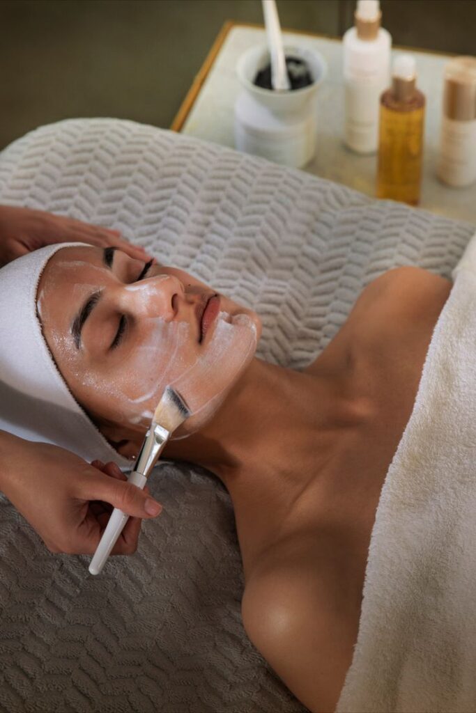 Person receiving a facial treatment with a brush application in a spa setting, promoting skincare and relaxation.