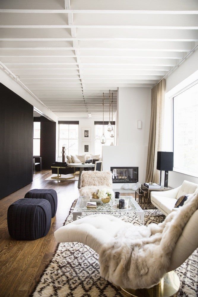 Modern living room with plush chairs, geometric rug, and large windows, featuring a cozy, minimalistic design.