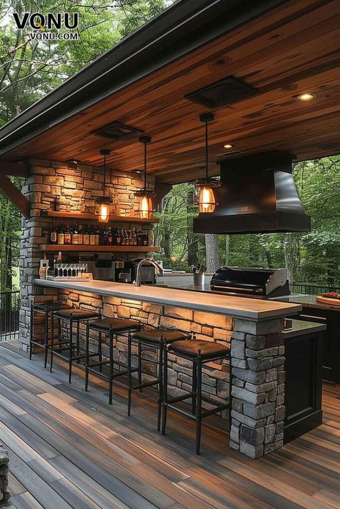 Outdoor kitchen with stone bar, cozy lighting, and forest view. Ideal for backyard entertaining and relaxation.