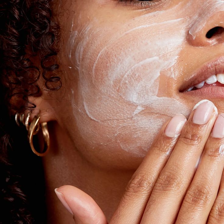 Person applying skincare cream to face for hydration and nourishment, focusing on healthy, glowing skin.