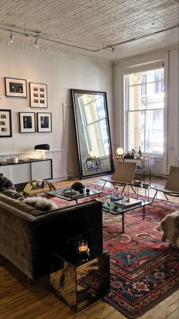 Chic living room with plush sofa, large mirror, artwork, and Persian rug accentuating elegant decor.