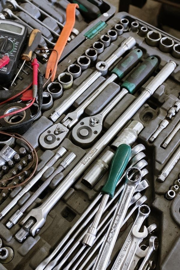 Assorted mechanic tools in a kit, including wrenches, sockets, and pliers, ideal for automotive repairs.