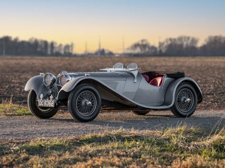 Classic vintage car parked on rural road at sunset, showcasing elegant design and timeless style.