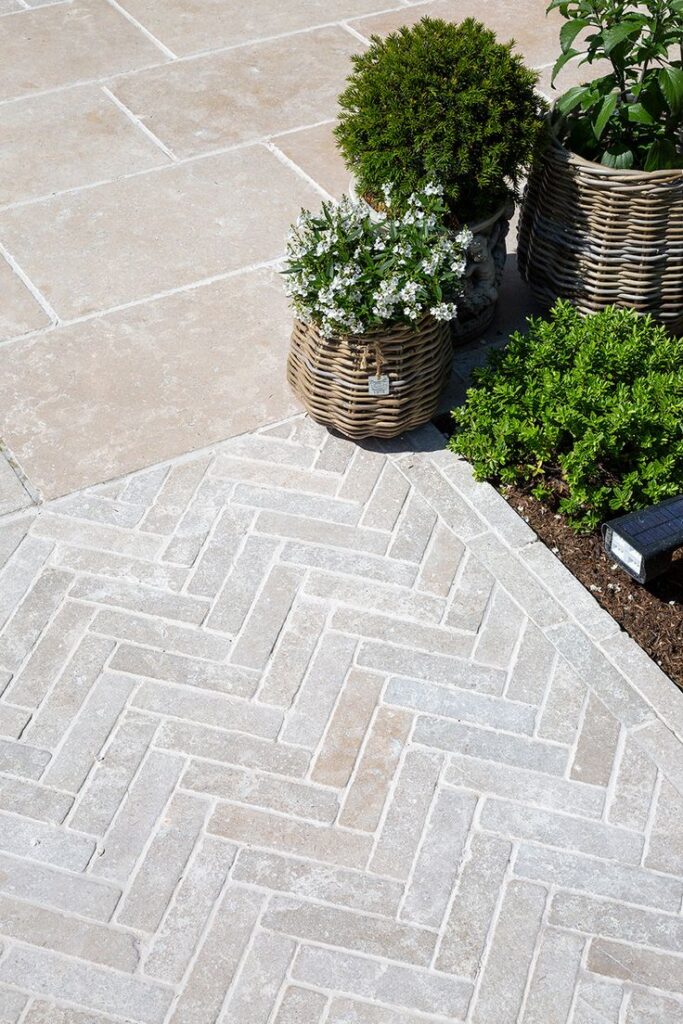 Elegant patio with herringbone tile pattern and wicker pots with greenery, enhancing outdoor decor.