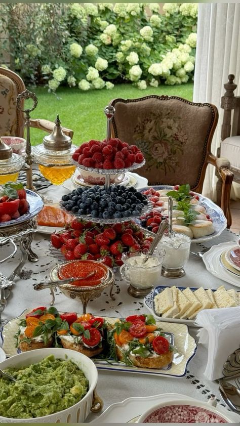 Elegant brunch spread with fresh berries, sandwiches, and salads on a garden table setting.