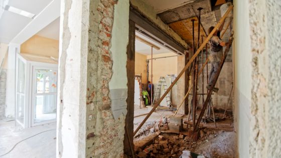 Interior renovation in progress with exposed brick walls and construction tools.