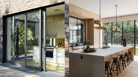 Modern kitchen with sliding glass doors, wooden accents, and large island for dining, open to outdoor greenery.