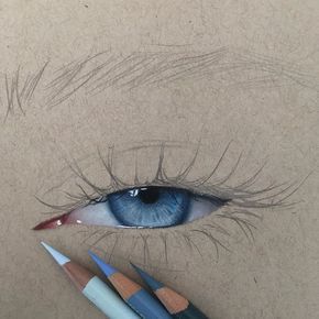 Realistic drawing of a blue eye with detailed shading using colored pencils on a textured paper background.