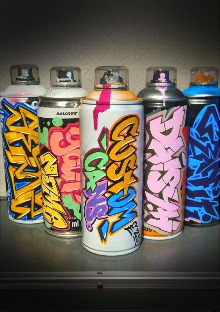 Colorful spray cans with graffiti-style labels in vibrant shades on a metallic surface.