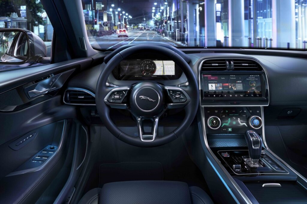 Luxury car interior with illuminated dashboard, modern steering wheel, and touchscreen display at night.