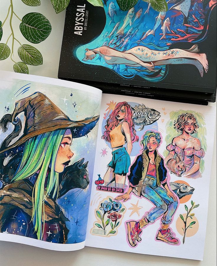 Art book open to colorful illustrations featuring fantasy characters and designs, surrounded by lush green leaves.