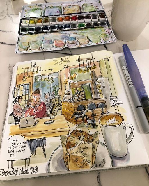 Sketch of a cozy café scene with a coffee cup and pastry, surrounded by art supplies and a journal entry.