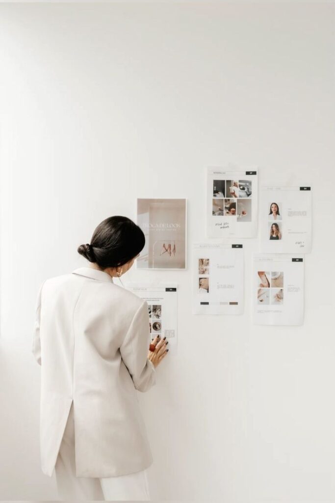 Person in white suit examining design mood board on a white wall.