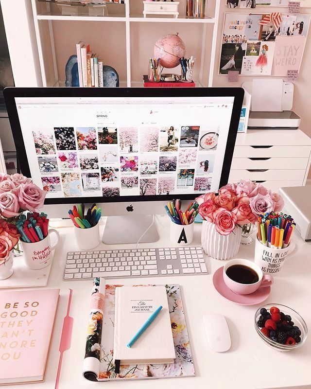 Chic desktop workspace with flowers, coffee, and colorful pens surrounding a computer displaying spring-themed images.