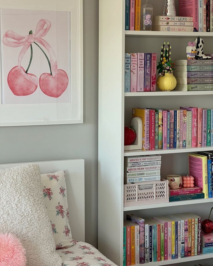 Cozy bedroom with floral bedding, a heart-shaped cherry painting, and bookshelves filled with colorful books.