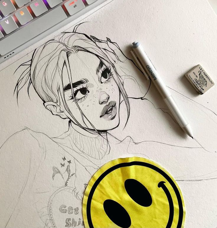 Black and white portrait sketch of a girl with a pen, eraser, and yellow smiley face sticker on a desk.