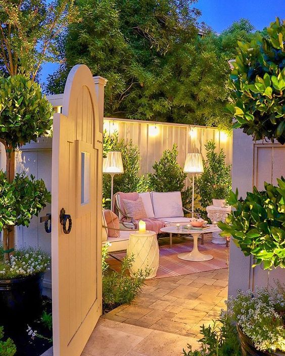 Cozy garden patio at dusk with seating, warm lights, and lush greenery for a tranquil outdoor retreat.