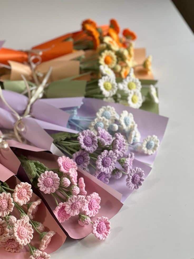 Colorful crochet flower bouquets arranged on a table, wrapped in pastel paper, showcasing intricate handmade designs.