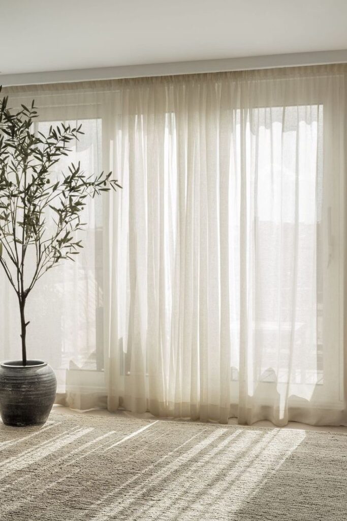 Bright room with sheer curtains and a potted plant, creating a serene and minimalist atmosphere.