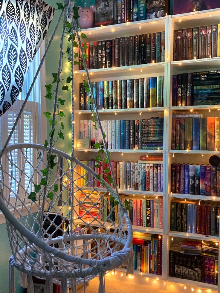 Cozy reading nook with a hanging chair, bookshelves, and string lights creating a warm, inviting atmosphere.