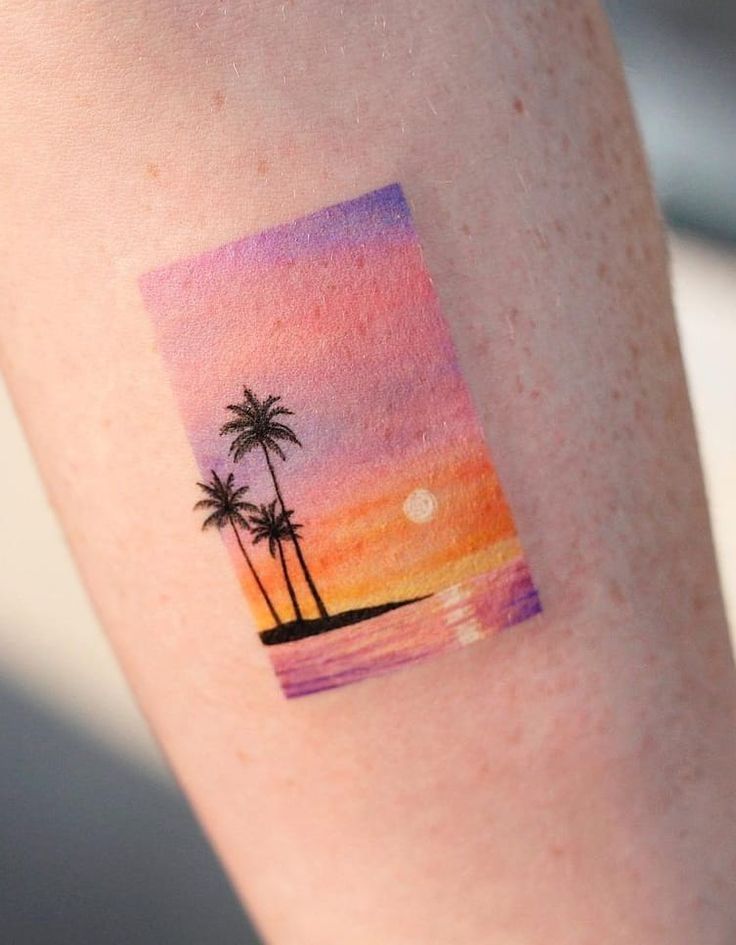 Minimalist sunset tattoo with palm trees, vibrant colors on skin – beach vibe art.