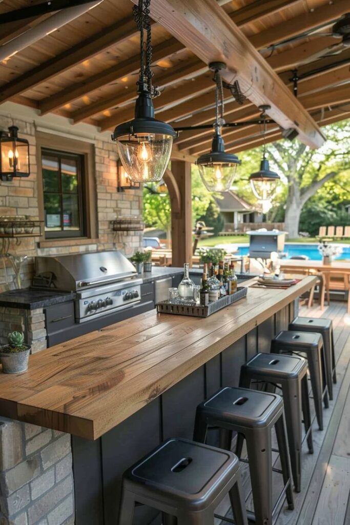 Rustic outdoor kitchen with wooden bar, stools, grill, and hanging lights, perfect for summer entertaining.