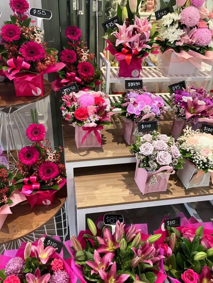 Floral shop display with vibrant arrangements of pink lilies, roses, and gerberas in gift boxes priced from  to 0.