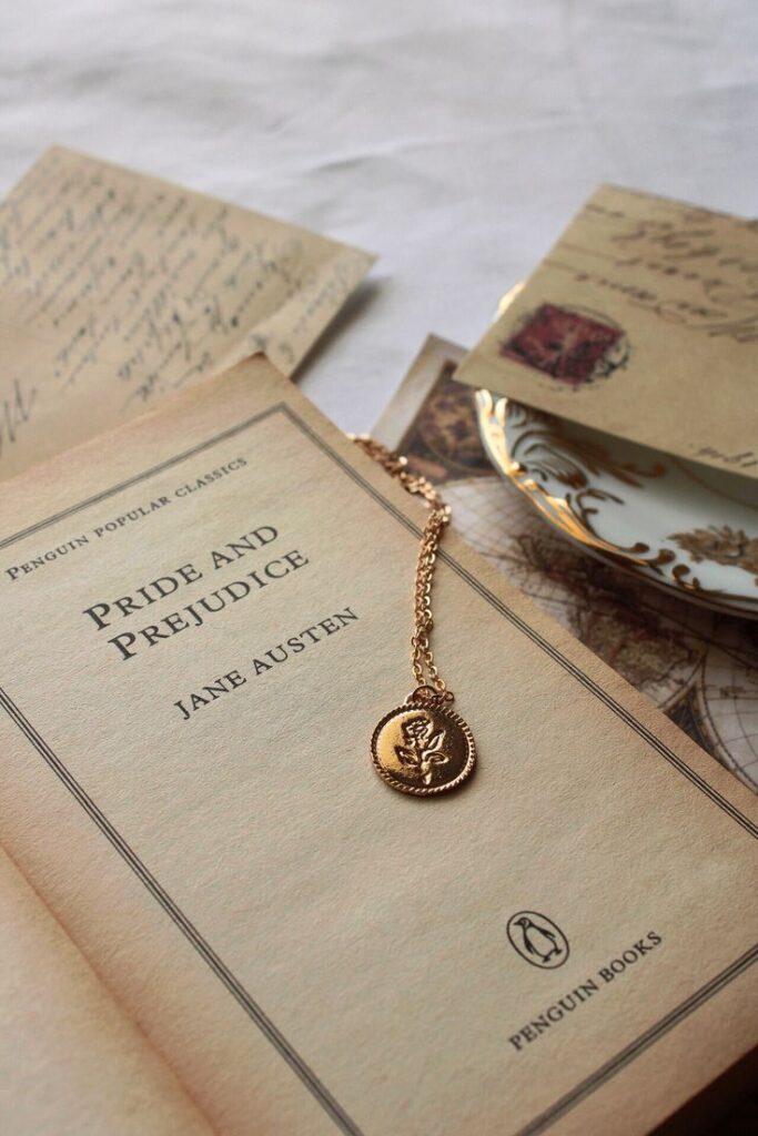 Pride and Prejudice book with vintage necklace and letters on table, creating a classic literary setting.